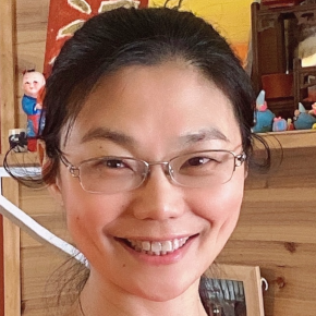 Asian woman with black hair and glasses smiling.